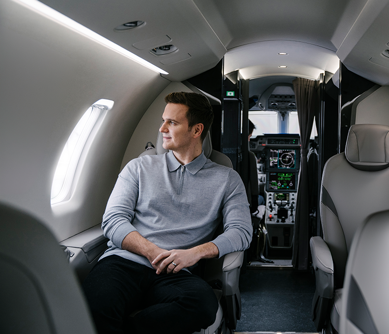 A man looking out the window of a private Air Partner plane