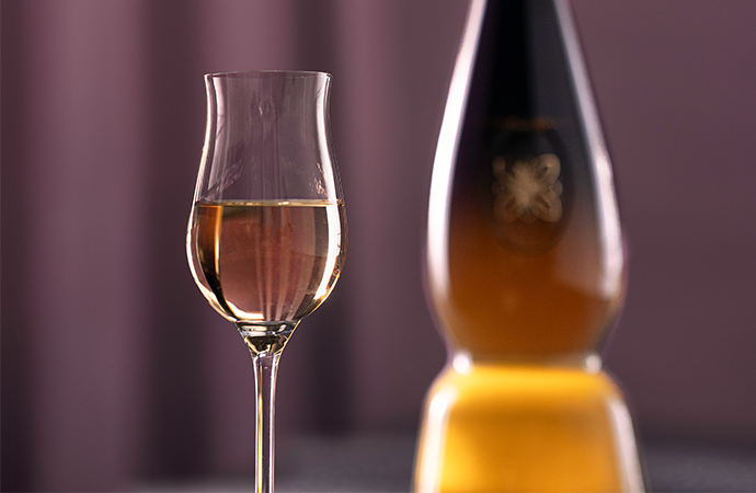 A glass of Clase Azul Tequila Gold with the bottle in the background