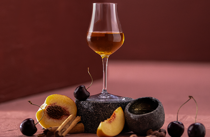 A glass of Clase Azul Tequila Ultra surrounded by the fruits and aromatics that make up its flavour profile