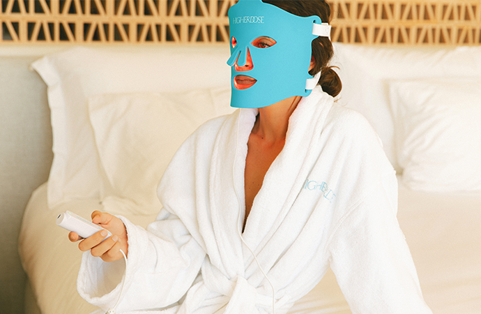 A woman relaxing in a robe wearing the Red Light Face Mask